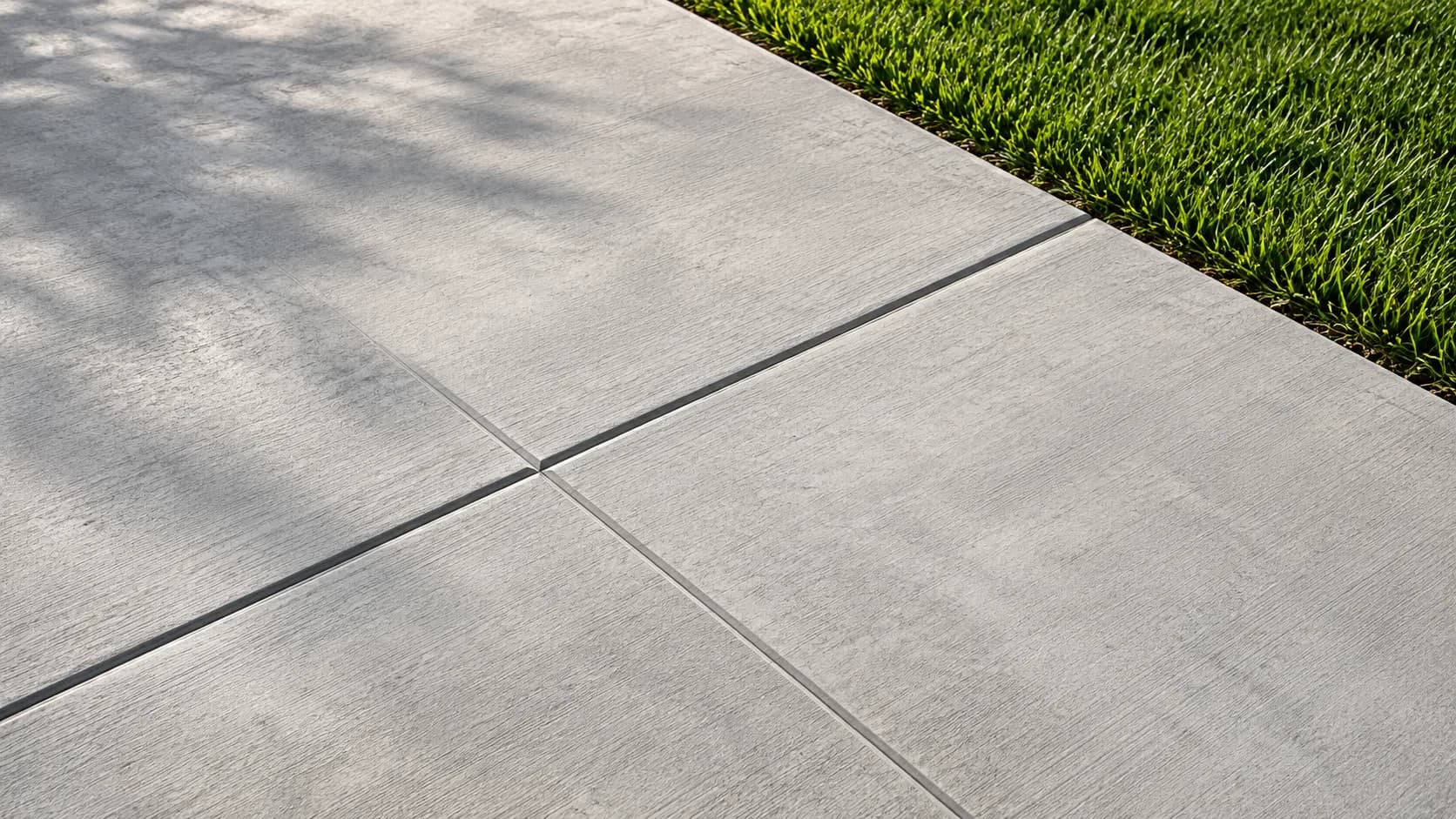 Concrete control-joint grid beside a lawn edge
